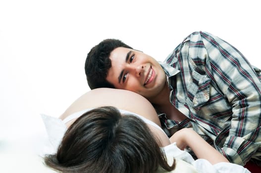 Portrait of young father listening to baby belly and smiling.
