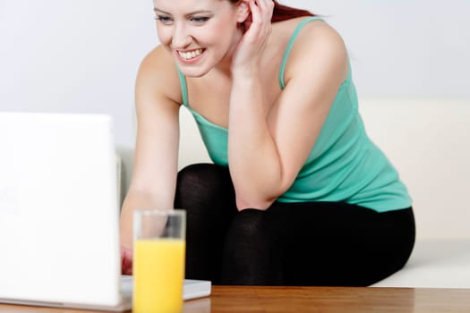 Happy smiling woman chatting with friends on a laptop at home on the sofa