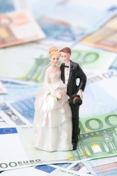 Wedding expense concept - wedding figurines (bride and groom) and money.