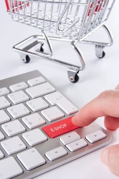 E-shop (e-commerce) concept - keyboard with e-shop text and shopping cart (shopping trolley) in background.
