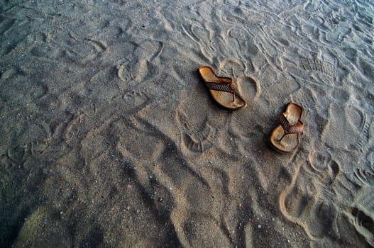 Flip flops in the sand at a beach.