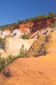 White and orange ocher hills and blue sky in the background. Ocher rocks (French Colorado) near Rustrel (Provence, Southern France)