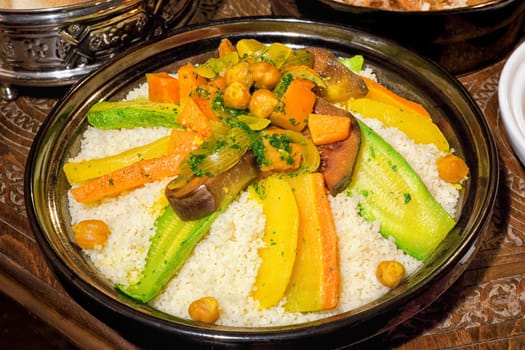Moroccan couscous tagine on carved, wooden table.