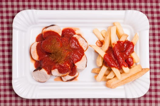 Currywurst with French fries in a white bowl
