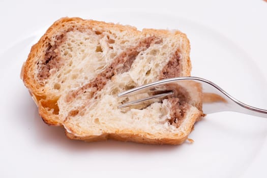 Piece of nut cake with fork on white plate