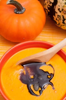 Pumpkin soup with pumpkin seed oil and wooden spoon