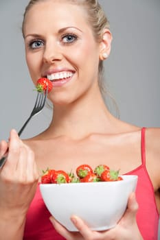 Beautiful young woman eating fresh summer berries