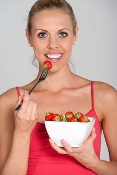 Beautiful young woman eating fresh summer berries