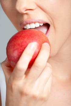 Beautiful young woman eating an apple wearing a white vest top
