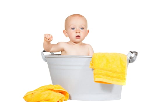Adorable young baby sitting in a zinc bath with colourful yellow towels isolated on white