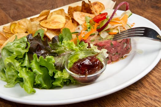 raw ground beef with chips and salad