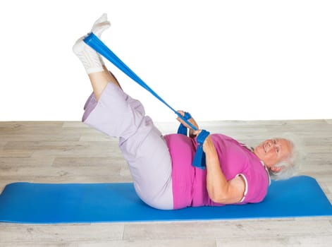 Retired lady doing exercises lying on a gym mat raising her legs in the air to strengthen her abdominal muscles