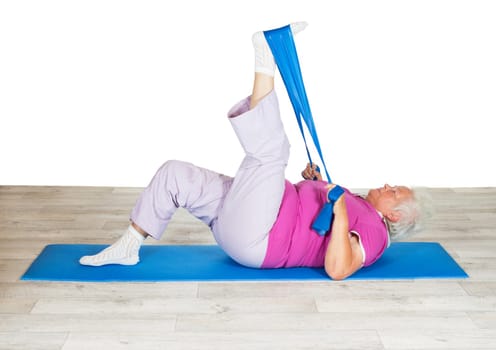 Senior woman exercising for mobility lying on a mat raising her leg in the air using a strap for leverage to improve mobility in her hip