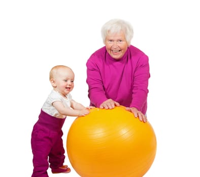Laughing grandmother pausing in her exercises as her inquisitive little baby grandchild comes over to investigate the pilatses ball