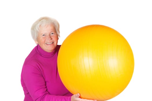 Elderly senior woman holding a yellow pilates or gym ball in her hand with a lovely radiant smile on her face