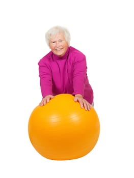 Cheerful retired lady leaning on a bright yellow pilates ball as she uses muscle control to improve her fitness and health