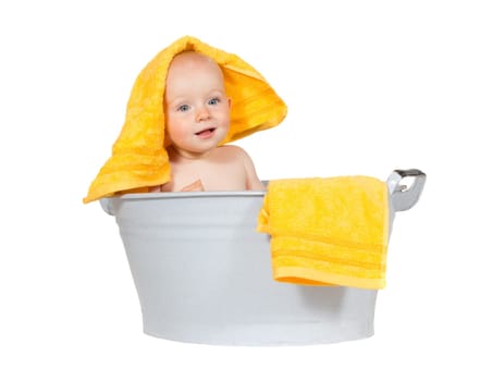 Young baby having fun at bathtime sitting in a zinc tub with a colourful yellow towel draped over its head isolated on white