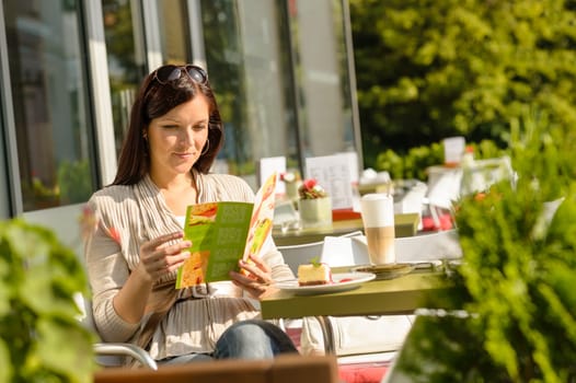 Woman looking at menu sitting cafe bar terrace choice dessert