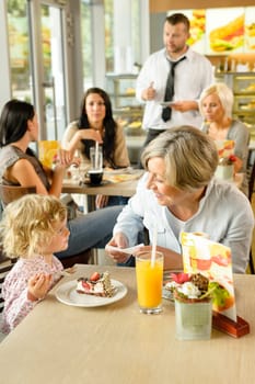 Child with grandmother at cafe eating cake sitting dessert restaurant