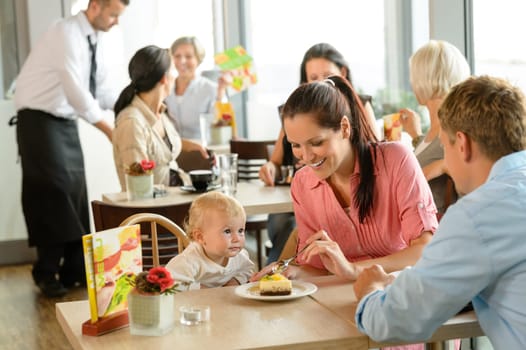 Couple feeding their child cake at cafe restaurant woman man