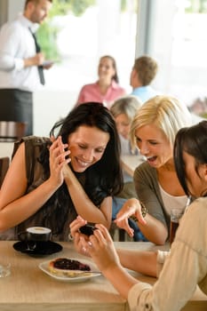 Friends looking at photographs and laughing cafe woman fun enjoying