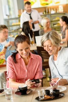Mother and daughter looking at pictures cafe women smiling camera