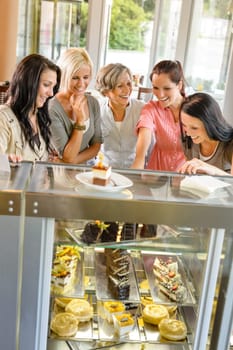 Group of friends looking at cakes cafe women happy choosing