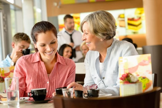 Mother and daughter relaxing in a cafe women restaurant happy