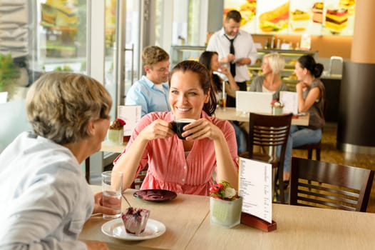 Senior woman with her daughter at cafe drinking eating happy