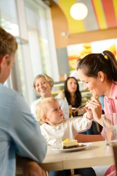 Father and mother feeding child cake cafe woman man eating