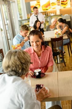 Senior woman with her daughter at cafe drinking eating happy