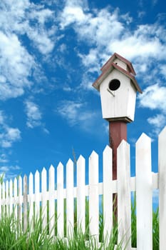 birdhouse with white fence and blue sky