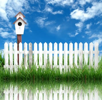 birdhouse with white fence and blue sky