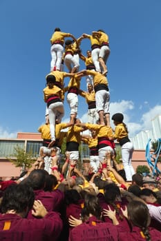 BARCELONA - SEPTEMBER 11: Some unidentified people called Castellers do a Castell or Human Tower, typical tradition in Catalonia, on September 11, 2012 in Barcelona, Spain.