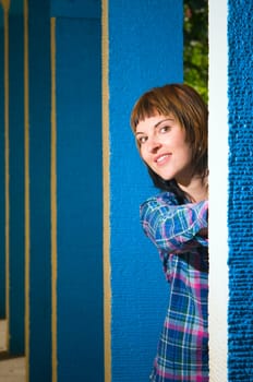 Upper body portrait of a young brunette woman posing between blue architectural pillars