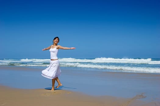 Beautiful happy woman dancing on the beach