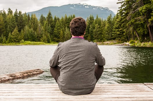 Young man meditating at the lake