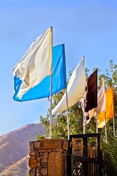 Generic portrait of a landscape incorporating plain multi coloured flags mounted on a stone wall at an entrance to a property. Location of shot was Rajasthan, India