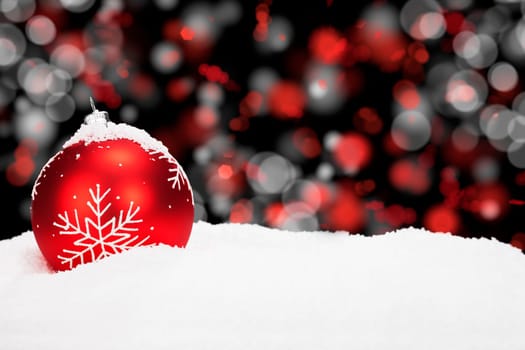 Red Christmas tree ball in the snow in front of red white light