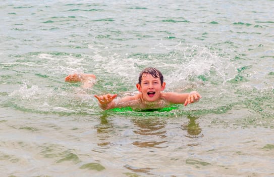 happy boy enjoys surfing in the waves at the beach