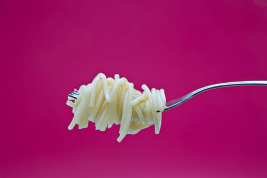 More noodles on metal chromed fork on background