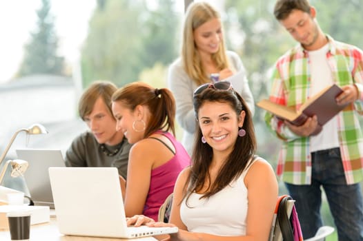 Teens studying in high-school library young pupils smiling laptop book
