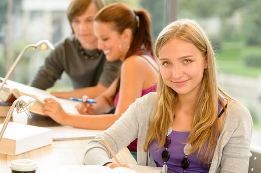 High-school student taking notes in study room smiling education campus