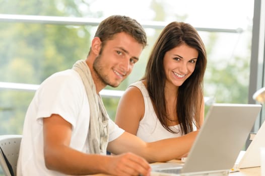 High-school pupils using laptop for school project academic library smiling