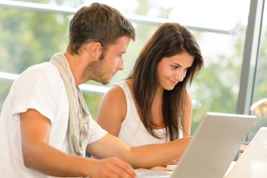 High-school pupils using laptop for school project academic library smiling