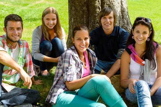 Students relaxing on meadow in park teens happy group leisure