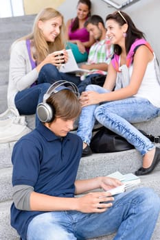 Students sitting on high-school stairs in break music reading teens