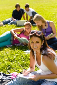 Students studying sitting on grass in park happy teens campus