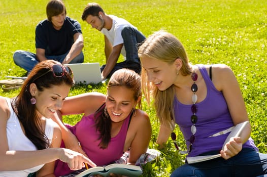 Teens studying in park reading book students happy campus research