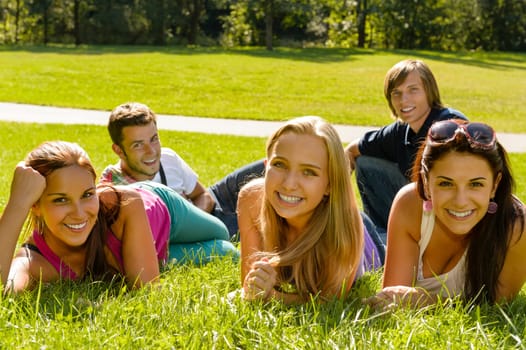 Students laying on grass in park campus smiling relaxing happy